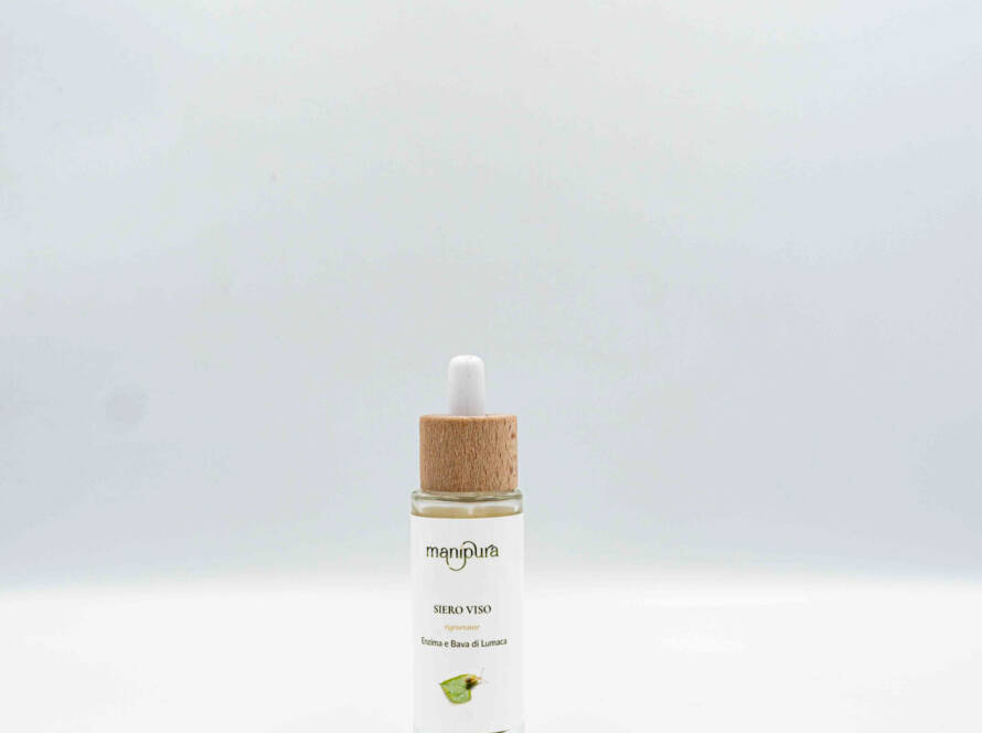 Flacone di siero viso rigenerante Manipura con enzima e bava di lumaca, dotato di contagocce con tappo in legno, su sfondo bianco.