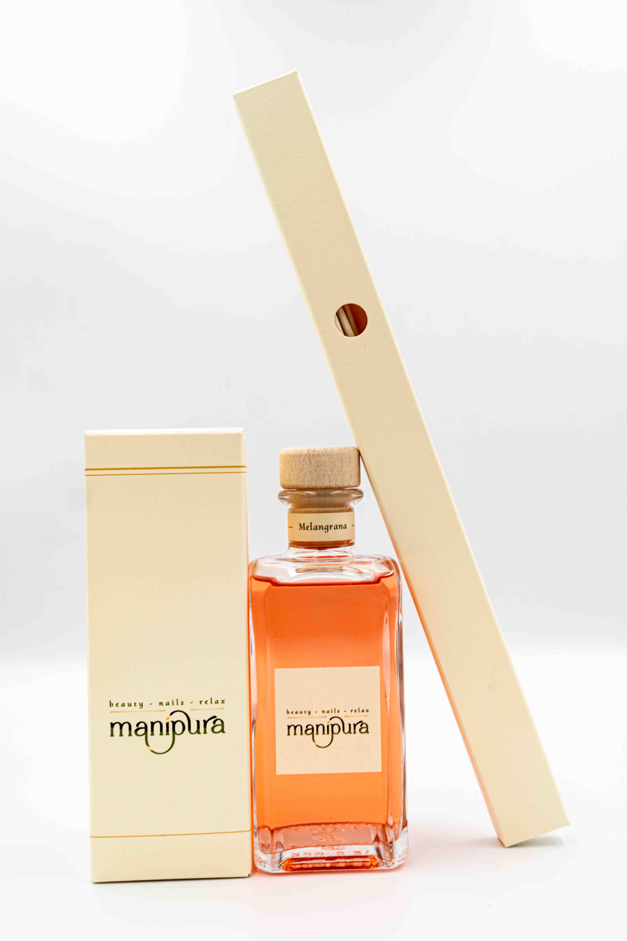 Profumatore ambiente Manipura alla fragranza Melagrana con bottiglia in vetro rosa, tappo in legno, su sfondo bianco.