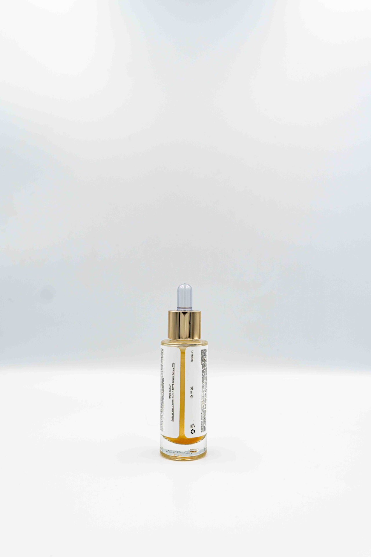 Flacone del siero viso illuminante Oro di Manipura mostrato dal retro, con etichetta ingredienti visibile e tappo contagocce dorato, su sfondo bianco.