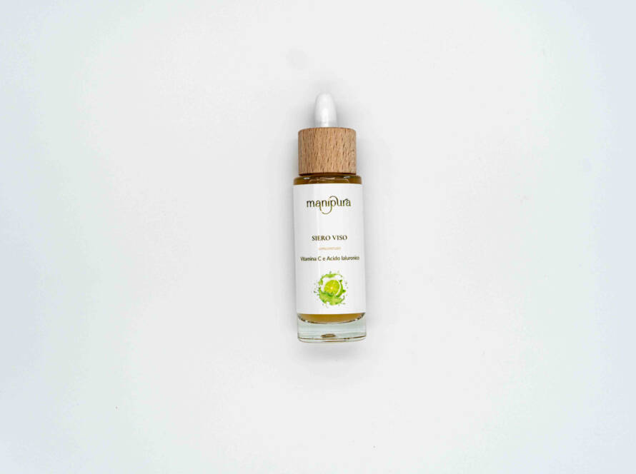 Flacone frontale del siero viso alla vitamina C Manipura, con tappo in legno e contagocce bianco, su sfondo chiaro.