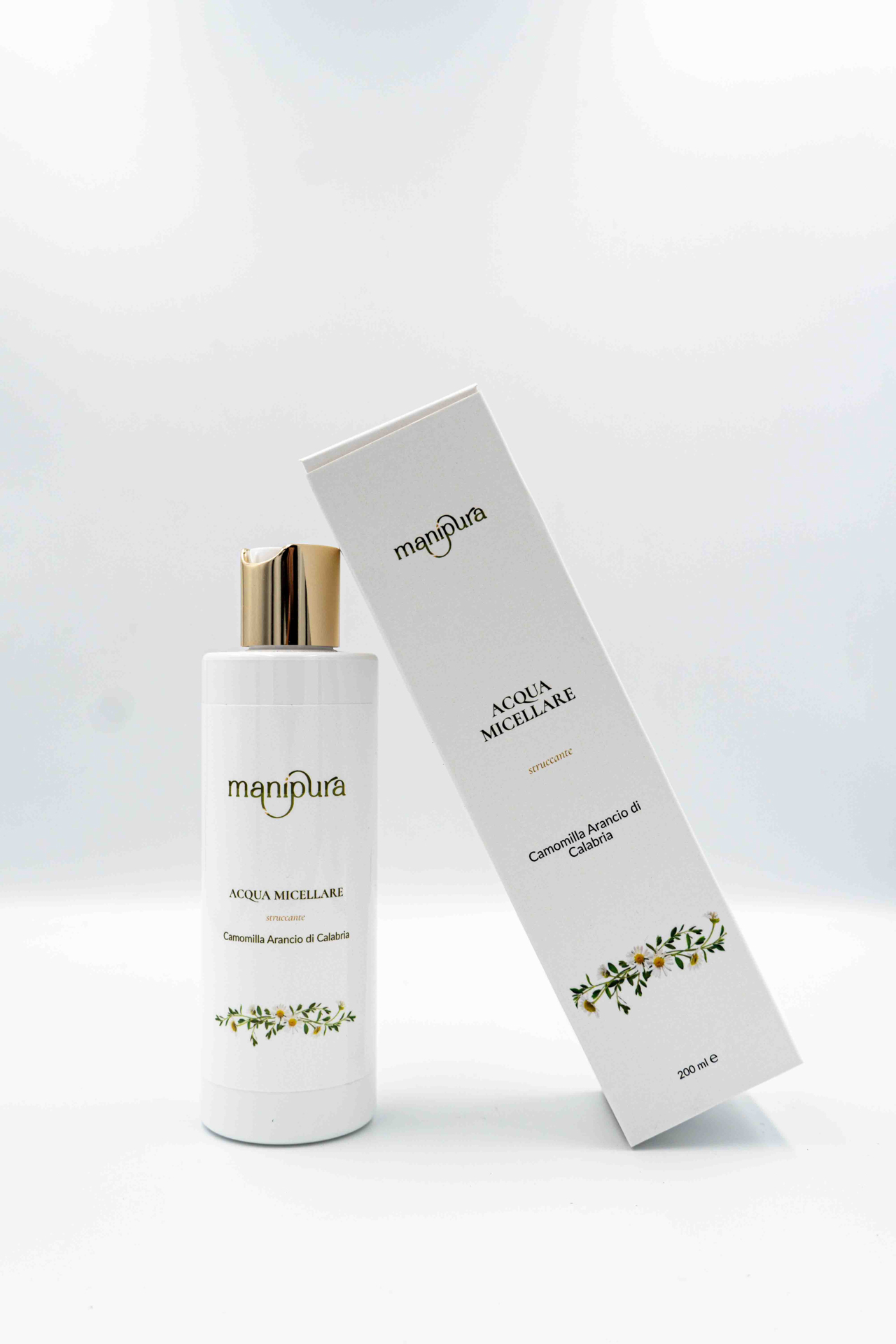 Flacone di Acqua Micellare Struccante Manipura con estratti di Camomilla e Arancio di Calabria, affiancato dalla confezione inclinata, su sfondo bianco.