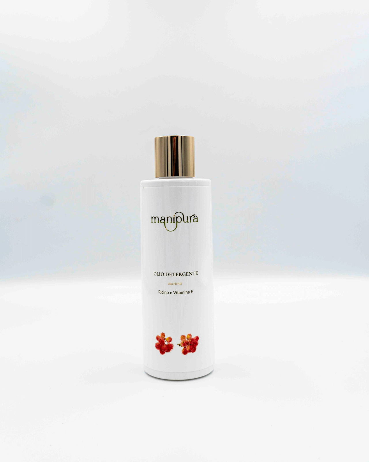 Flacone frontale di olio detergente Manipura con ricino e vitamina E, tappo dorato e grafica floreale su sfondo bianco.